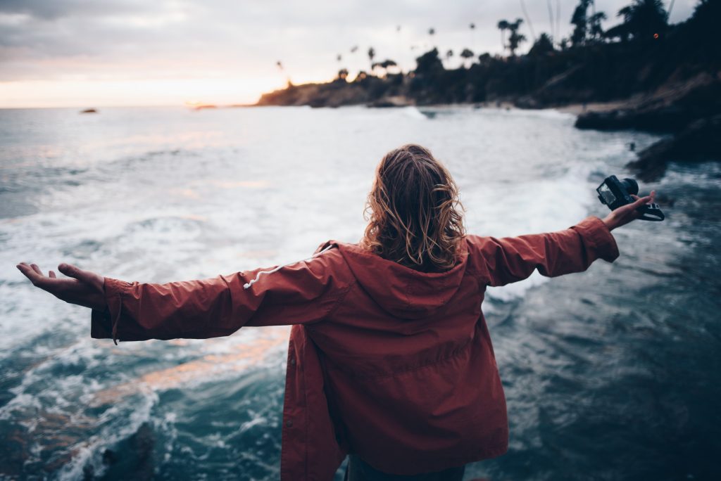 Header image for dichloroacetate sodium cancer therapy page. Woman with outstretched arms standing on beach.