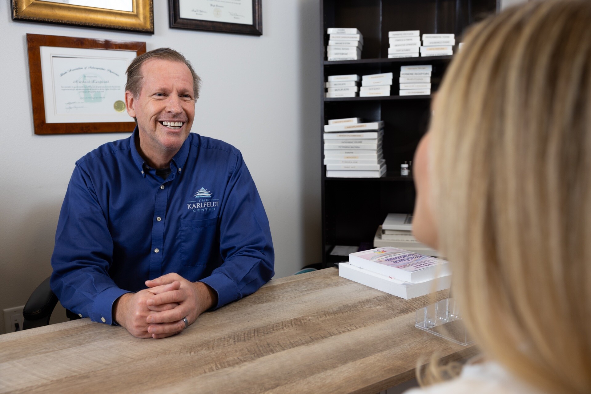 Dr. Karlfeldt speaking with a person seated across his desk at The Karlfeldt Center.