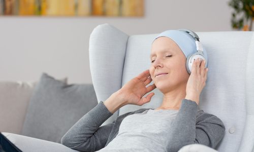 Woman,With,Cancer,Listening,To,Music,On,Headphones,At,Home